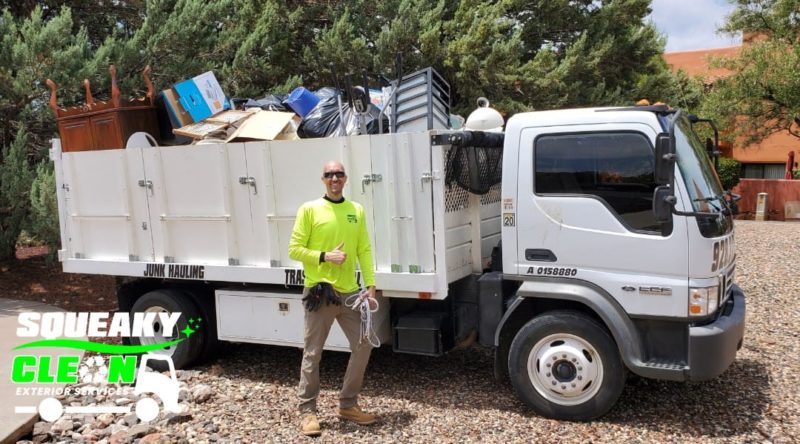squeaky clean junk removal expert standing in front of truck full of junk after junk removal services